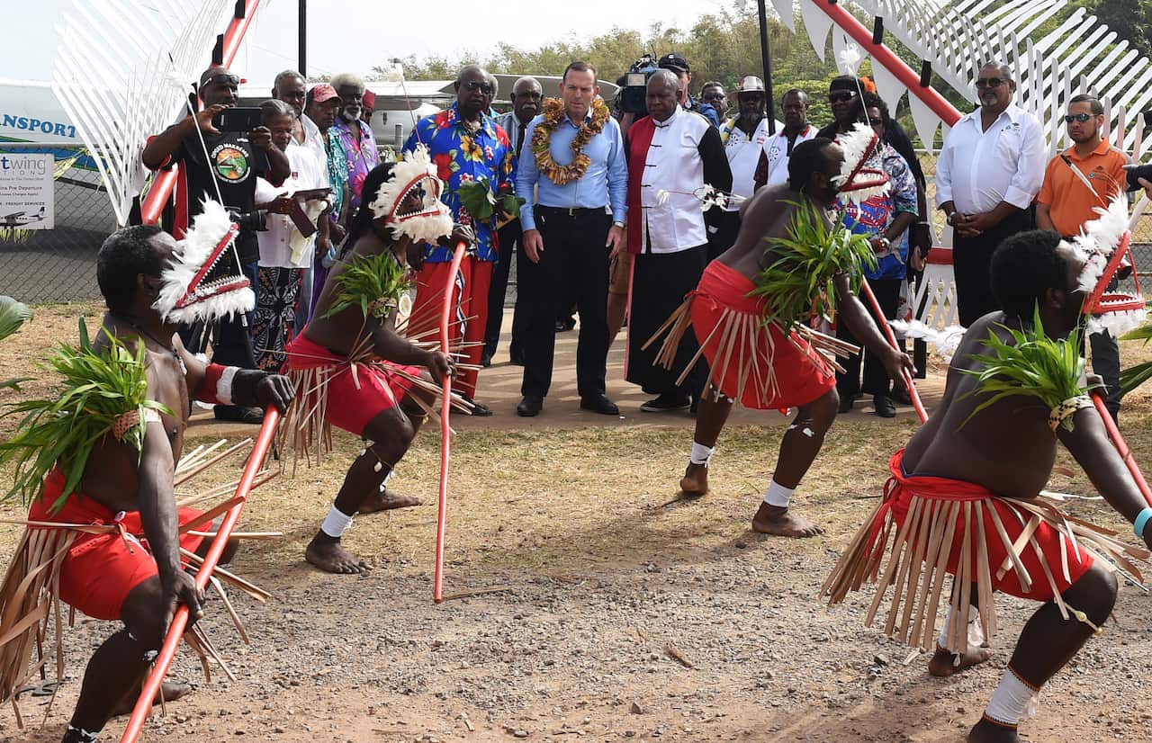 Prime minister Tony Abbott is given a traditional welcome as he arrives to visit the grave of land rights activist Eddie Mabo on Mer Island in the Torres Strait (AAP)