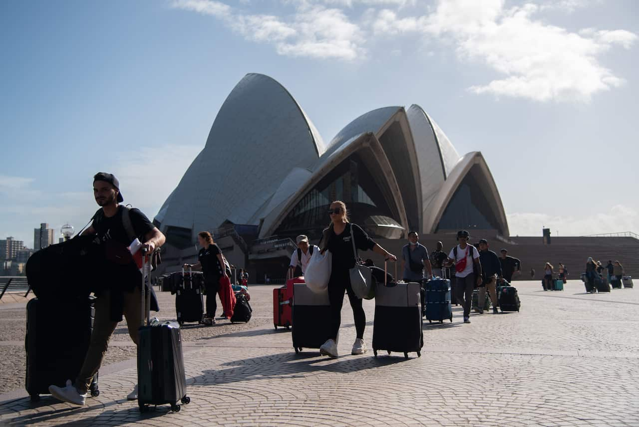 Crew members of the Cruise Ship 'Ovation of the Seas' walking past the Sydney Opera House after disembarking from the ship.