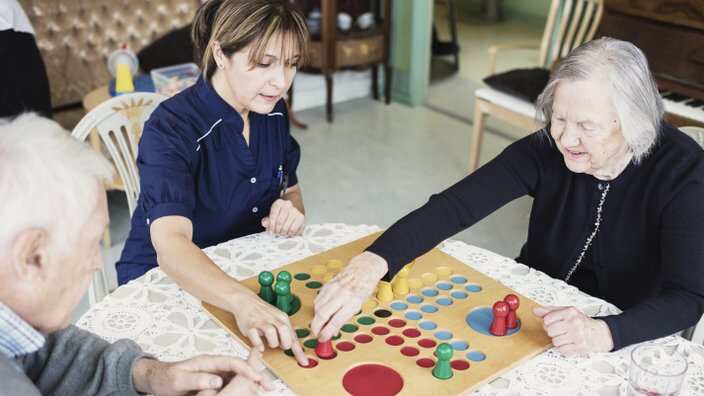 Caretaker playing Ludo with seniors at nursing home