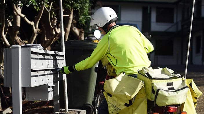 A postman on a motorbike delivers letters
