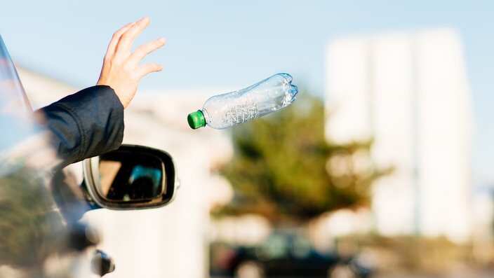Woman throwing bottle out of car window.