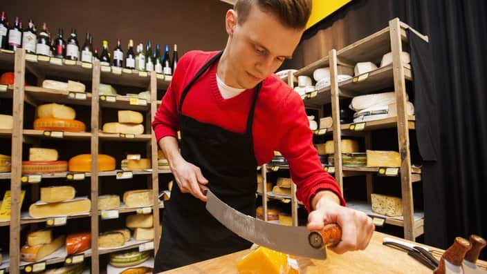 A salesperson cutting cheese in a store