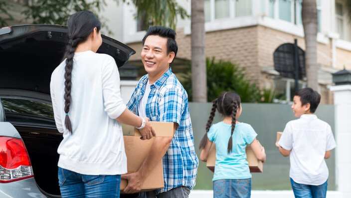 Parents and children unloading boxes from car to the new house