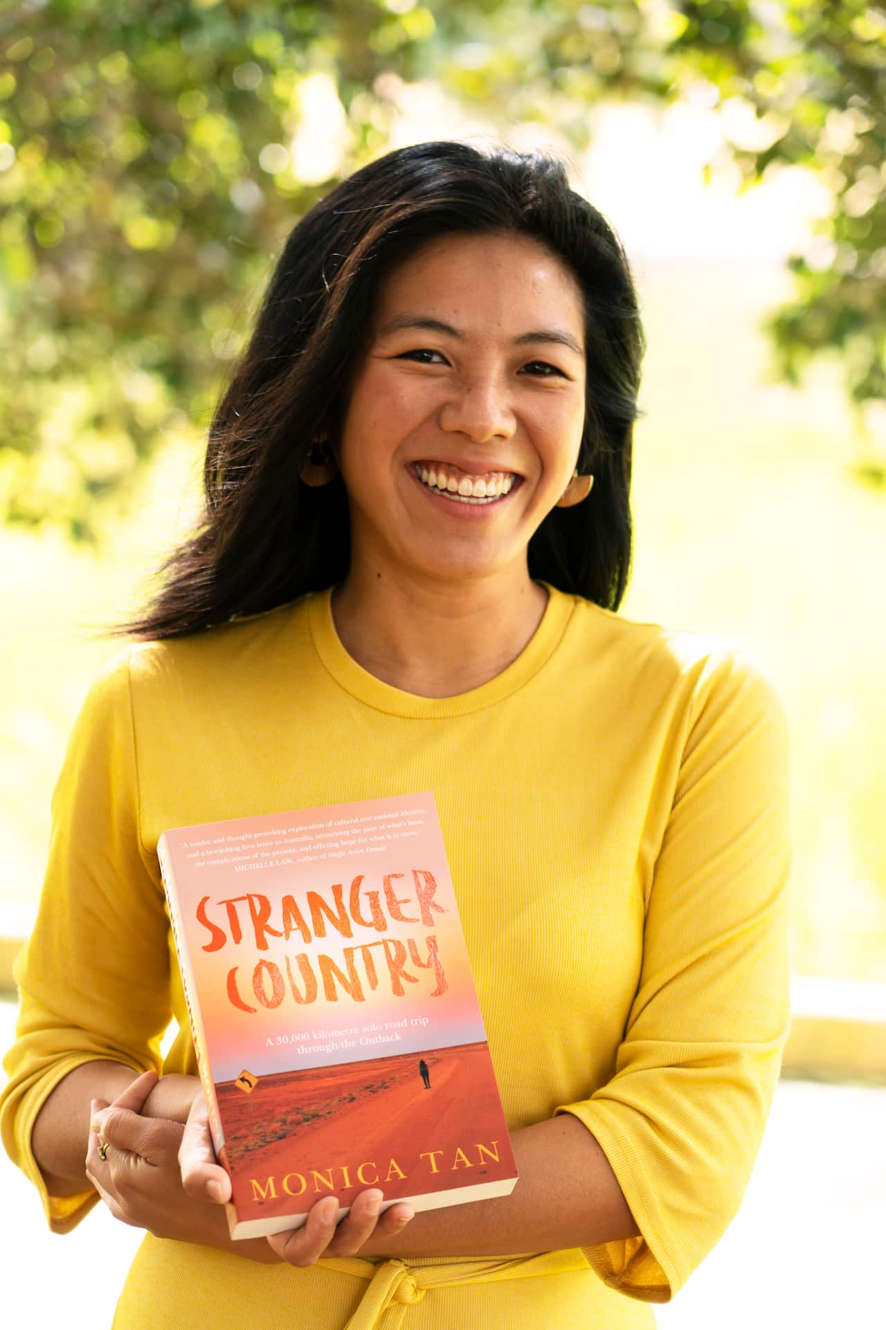 Monica Tan holding her book, Stranger Country.