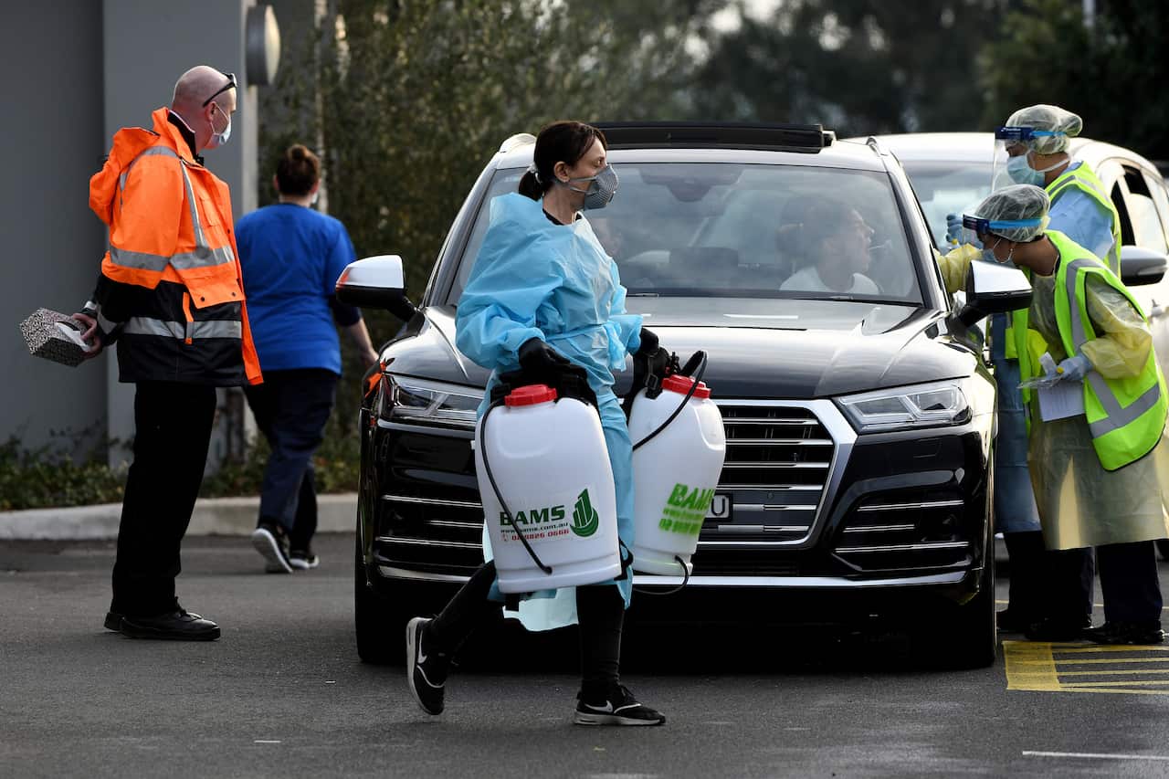 A cleaner dressed in Personal Protective Equipment leaves the Crossroads Hotel.