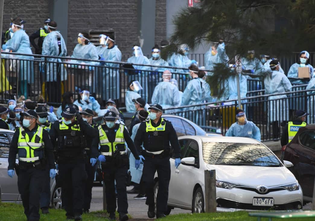 Victoria Police officers and healthcare workers line up outside a public housing tower in North Melbourne.