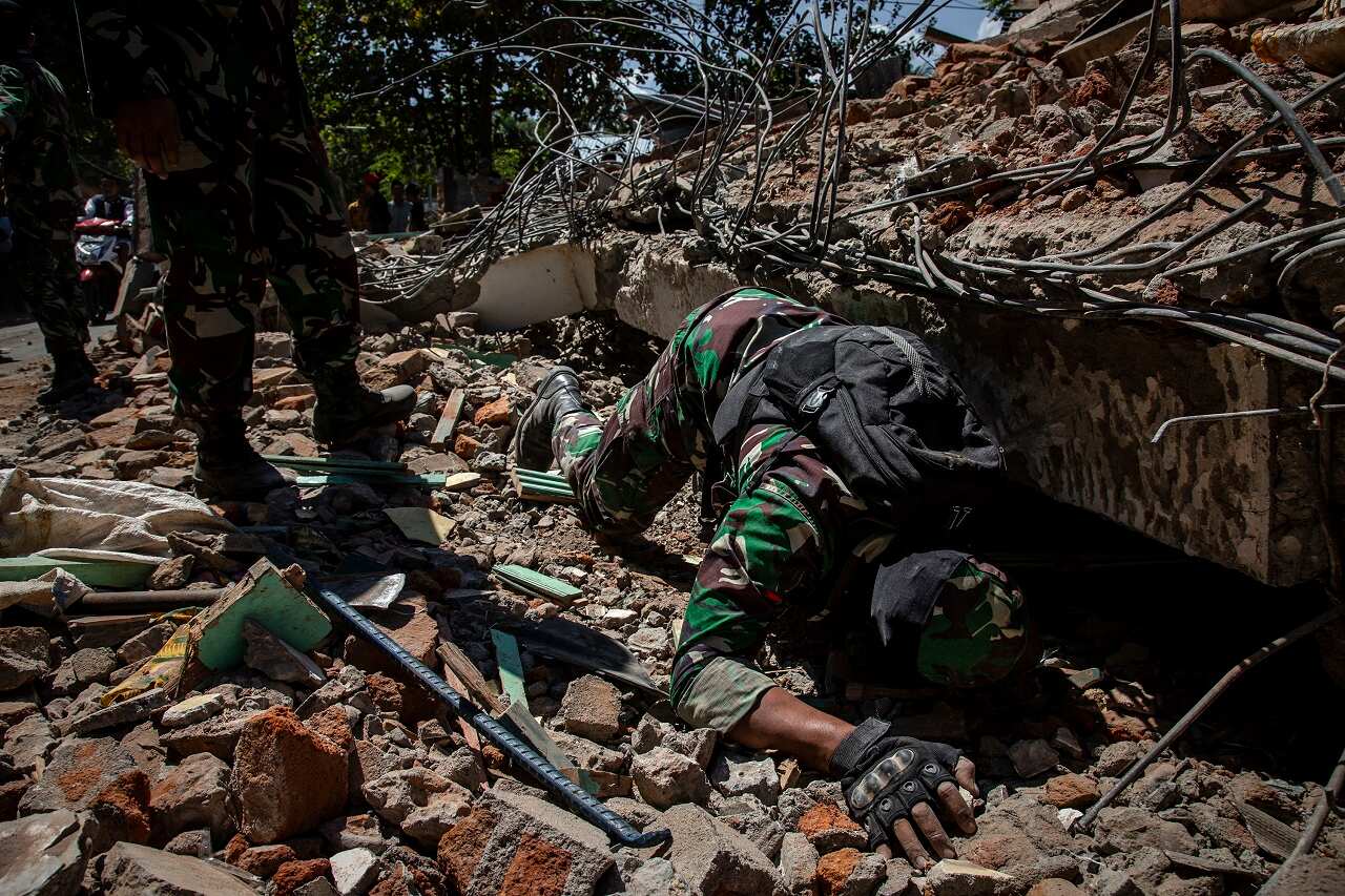 Indonesian soldiers look for victims at a collapsed house in Lombok following the Indonesian earthquake.