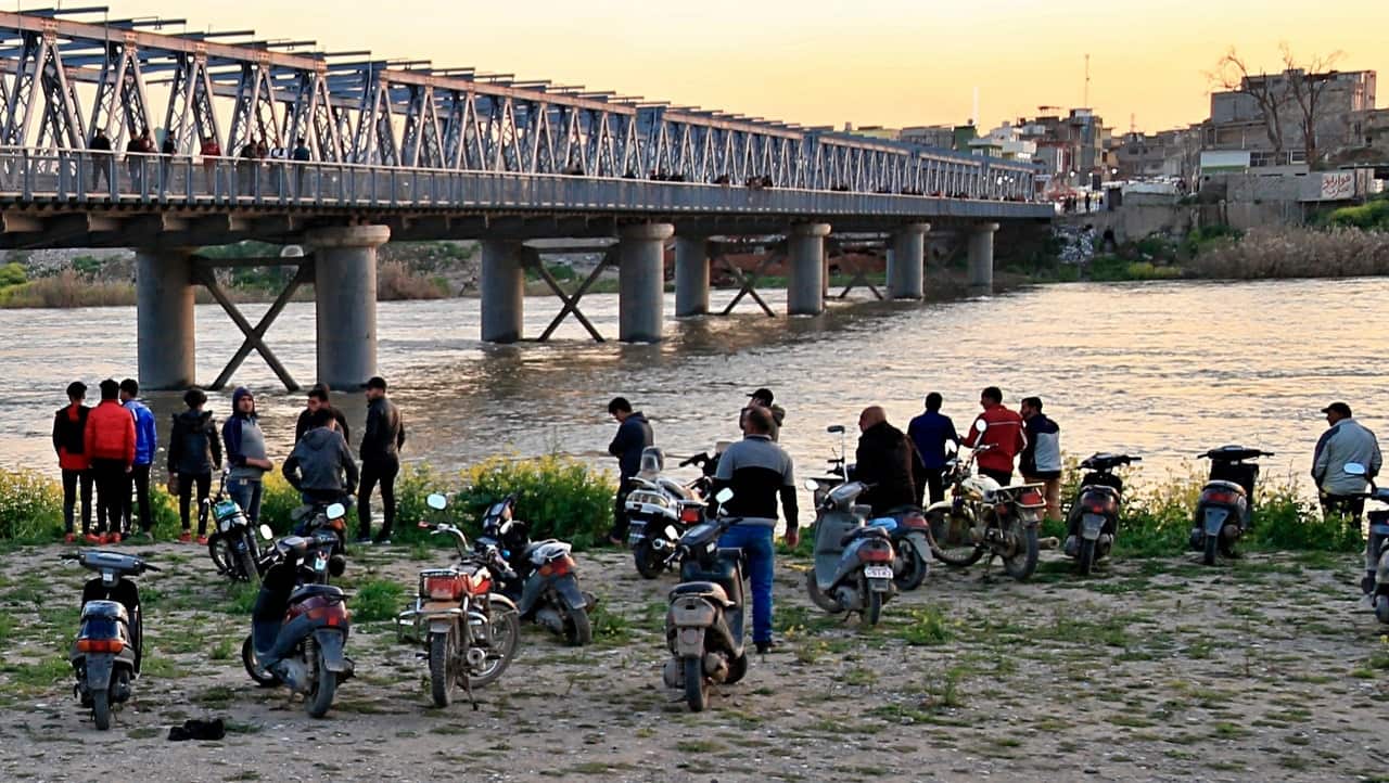 People and relatives of victims waiting on the bank of the Tigris river where the ferry sank in Mosul.