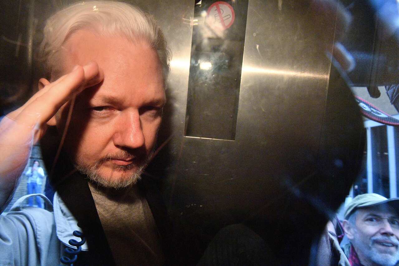 WikiLeaks founder Julian Assange gestures from the window of a prison van.