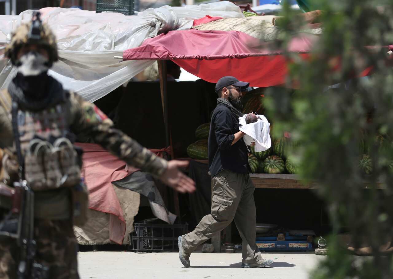 An Afghan security officer carries a baby (AAP)