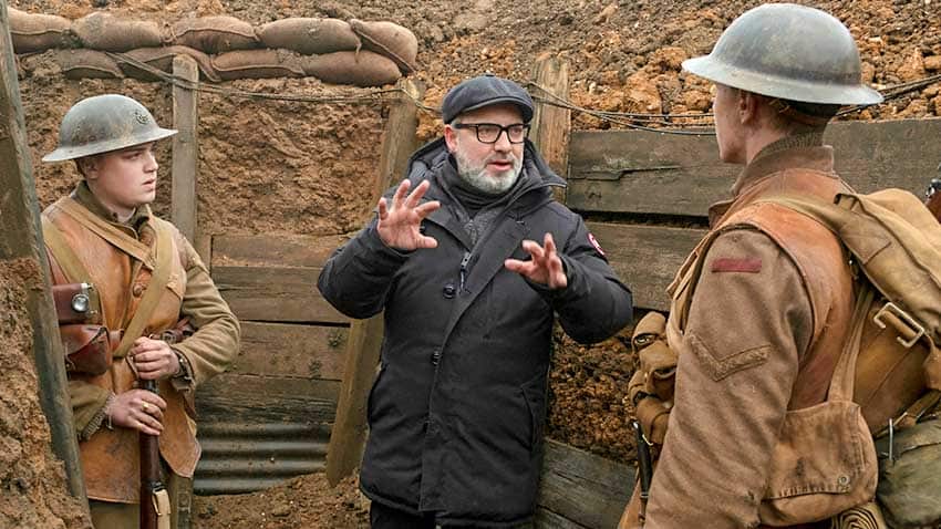 This image released by Universal Pictures shows Dean-Charles Chapman, left, director Sam Mendes, center, and George MacKay on the set of "1917." 