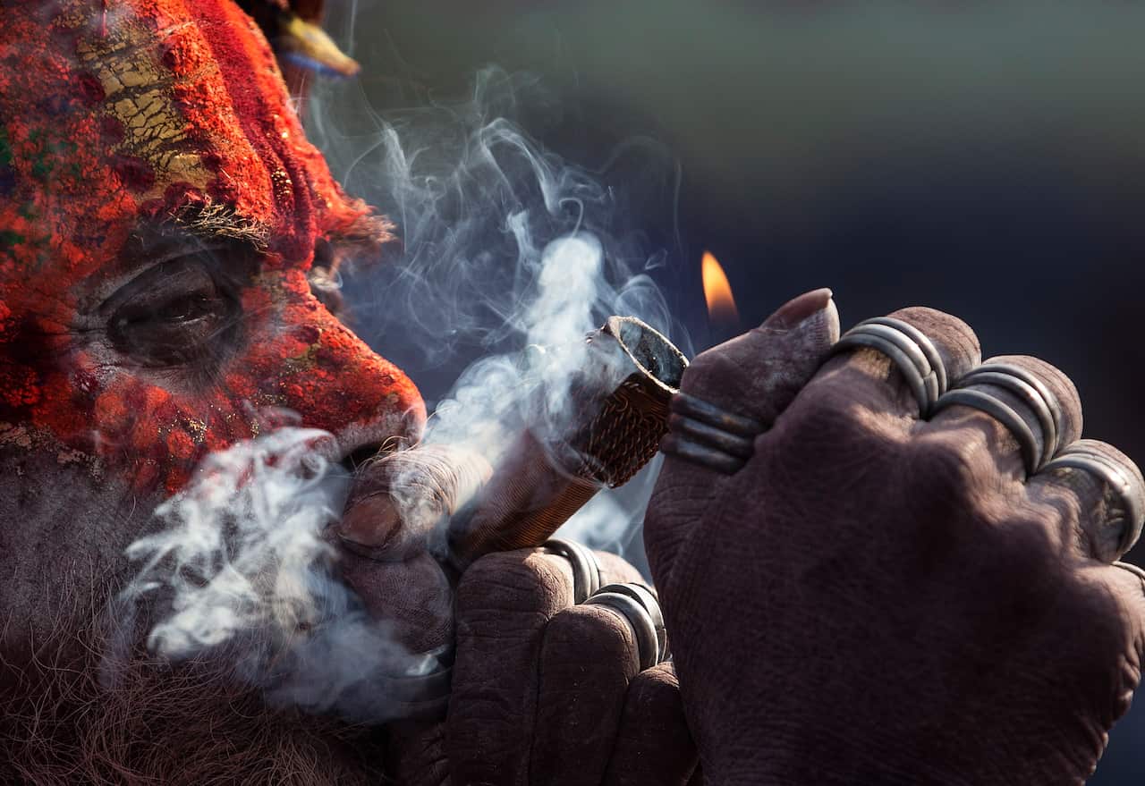 A sadhu, or holy man, smokes marijuana from a clay pipe at the Pashupati Temple in Kathmandu