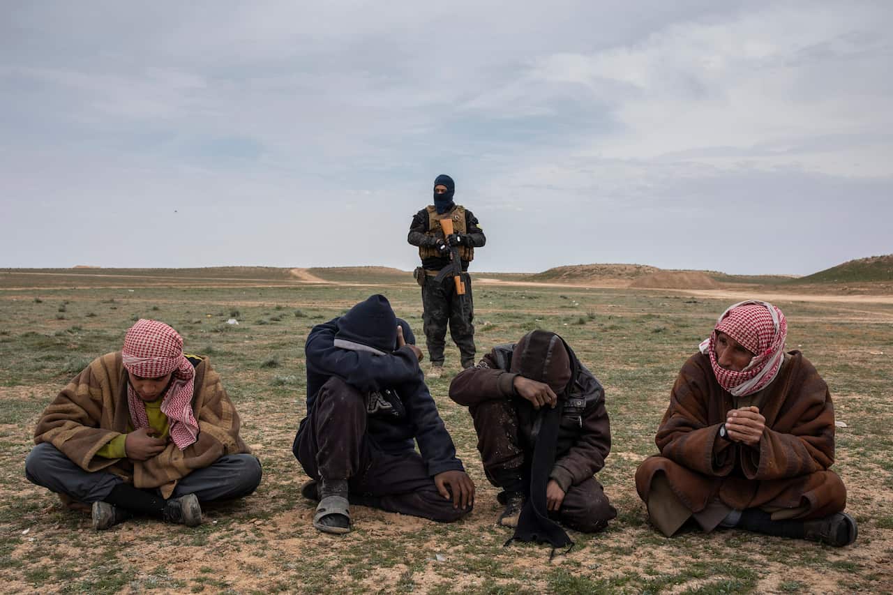 Men who fled the last village held by the Islamic State group wait to be questioned by coalition forces in the province of Deir el-Zour, Syria, on Feb. 7, 2019. (Ivor Prickett/The New York Times)