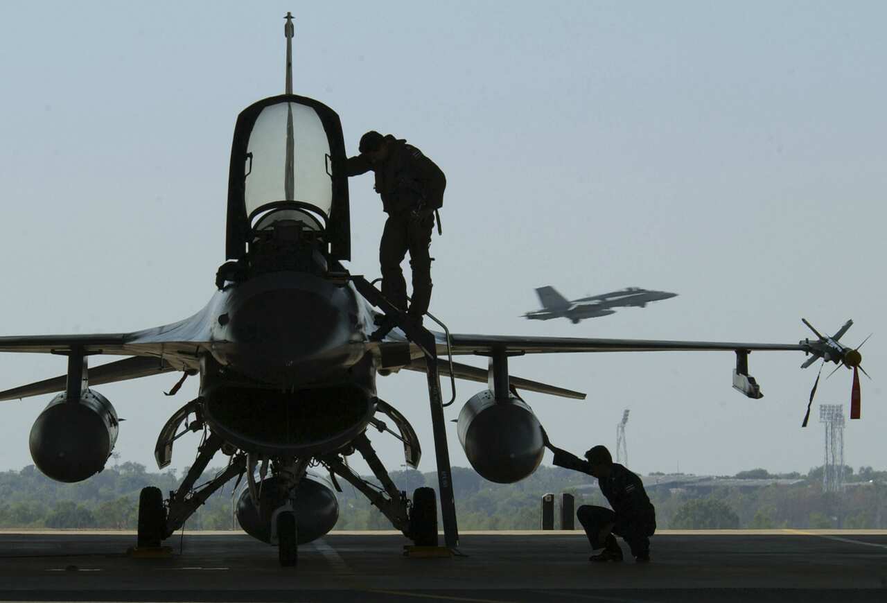 A pilot and technician of the Royal Thai Air Force prepare a F-16 Falcon for launch as a Royal Australian Air Force F/A-18 Hornet takes off for a training mission in exercise Pitch Black over Darwin, Australia, Tuesday July 20, 2004.The three-week exercis