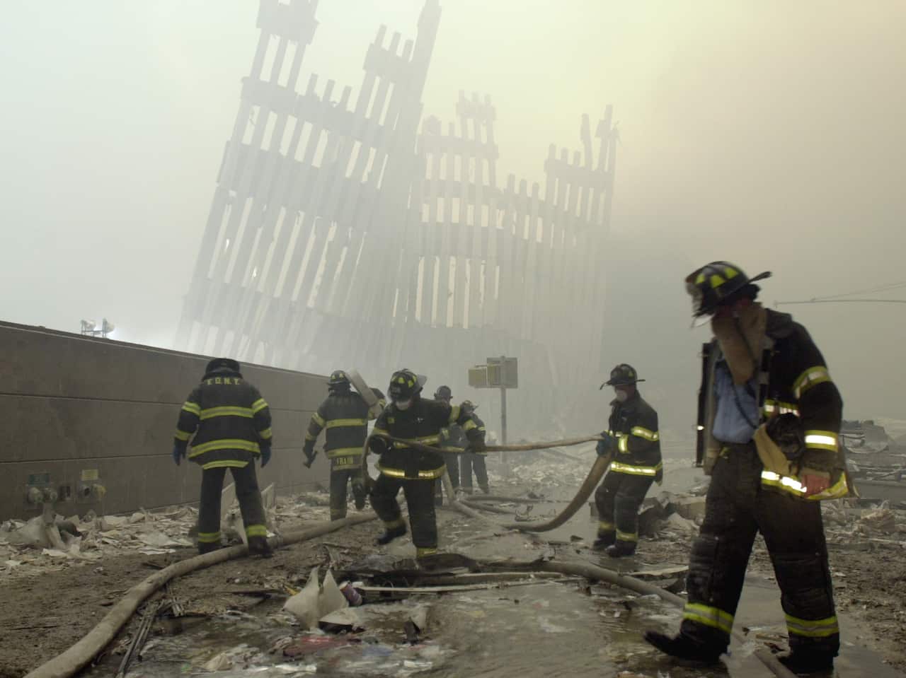 Firefighters work beneath the destroyed mullions, the vertical struts which once faced the soaring outer walls of the World Trade Center