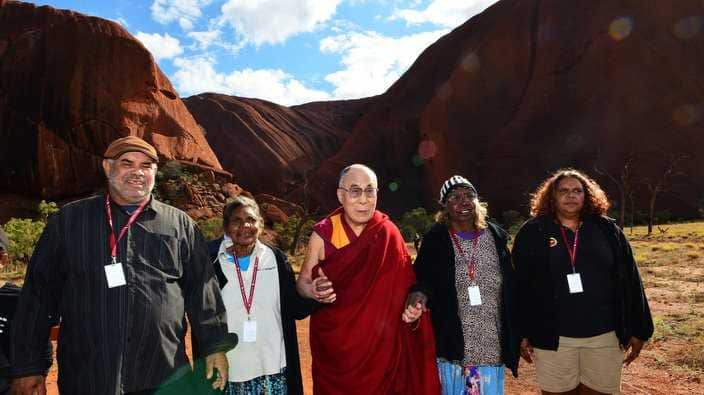 The Dalai Lama is greeted on his arrival at Uluru, Northern Territory, Australia, Saturday, June 13, 2015.The Dalai Lama is in Australia as part of his Wisdom of Forgiveness tour. Daisy Walkabout, (white shirt) Judy Trigger (stripped beanie) and Rita Okai