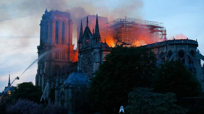 Massive plumes of yellow brown smoke is filling the air above Notre Dame Cathedral and ash is falling on tourists and others around the island that marks the center of Paris. 