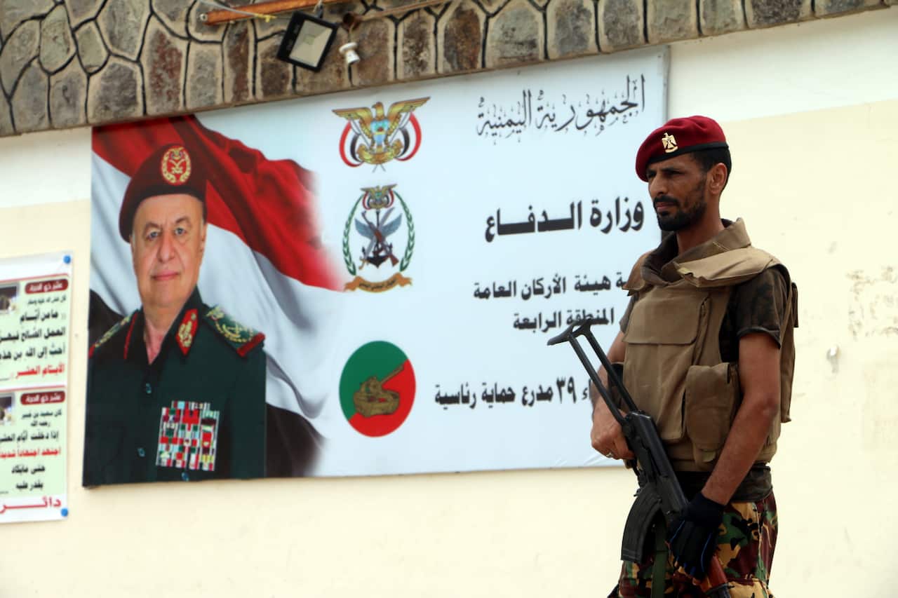 An armed member of a separatist southern group stands guard near a banner depicting a portrait of Yemeni President Abdo Rabbo Mansour Hadi