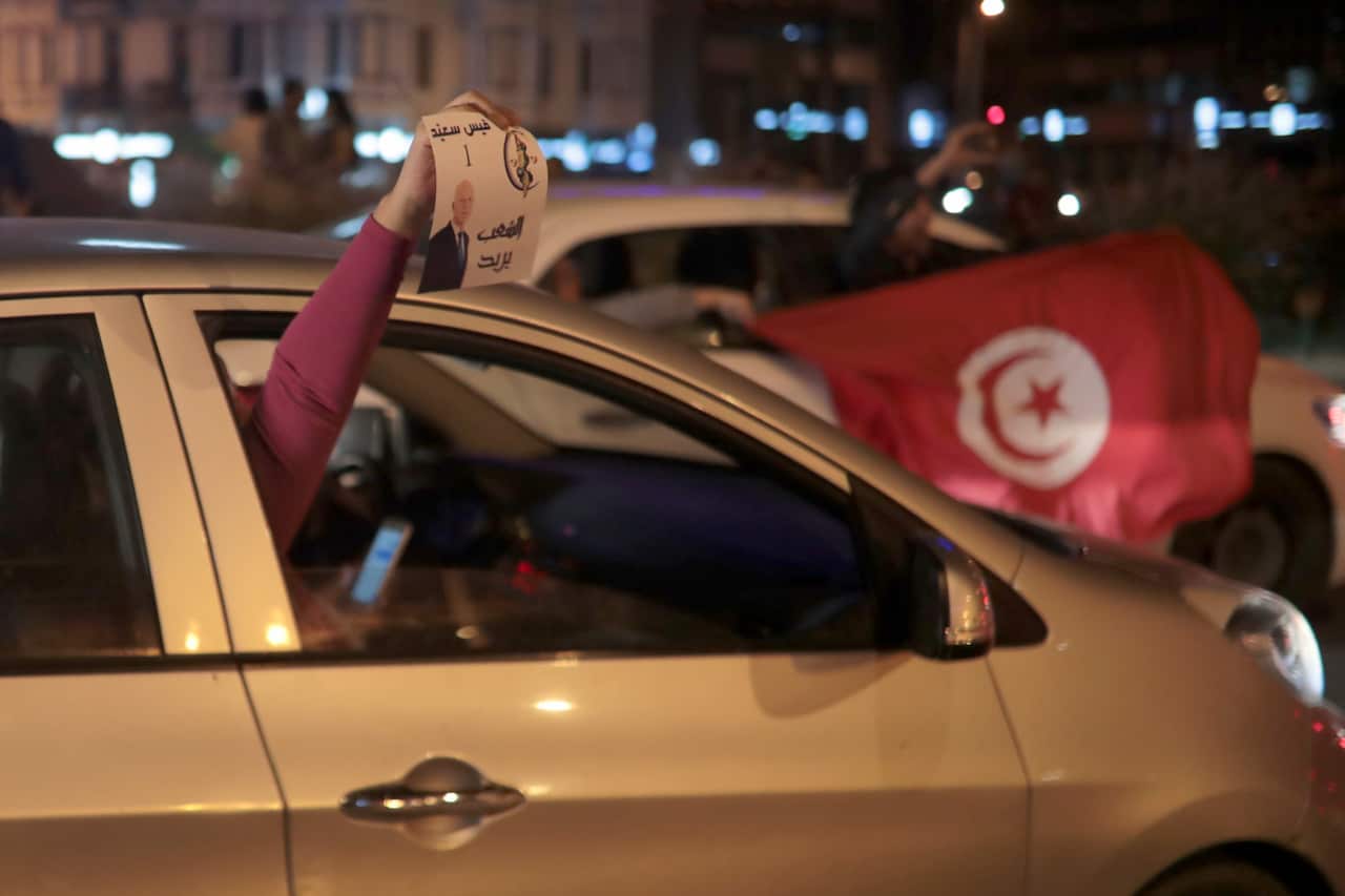 Peopel celebrate with a poster of Kais Saied and Tunisian flags in Tunis, Sunday, Oct. 13, 2019.