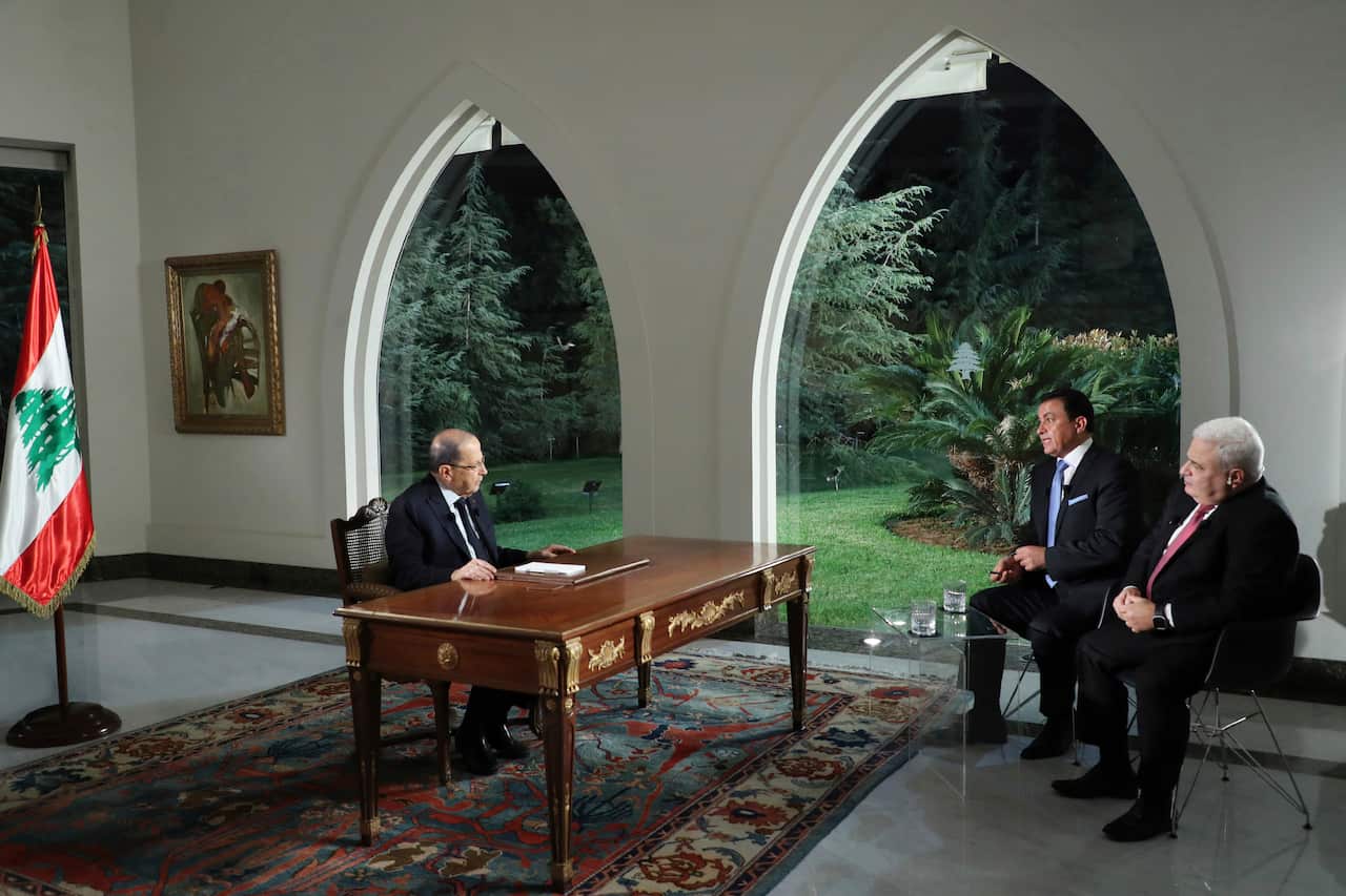 Lebanese President Michel Aoun, left, speaks during a TV interview, at the presidential palace, in Baabda, east of Beirut, Lebanon