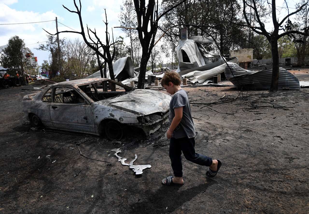 Eight year-old Jarrod McInnes walks next to the remains of a house that his family was about to buy and was destroyed by bushfires in Rappville, NSW 