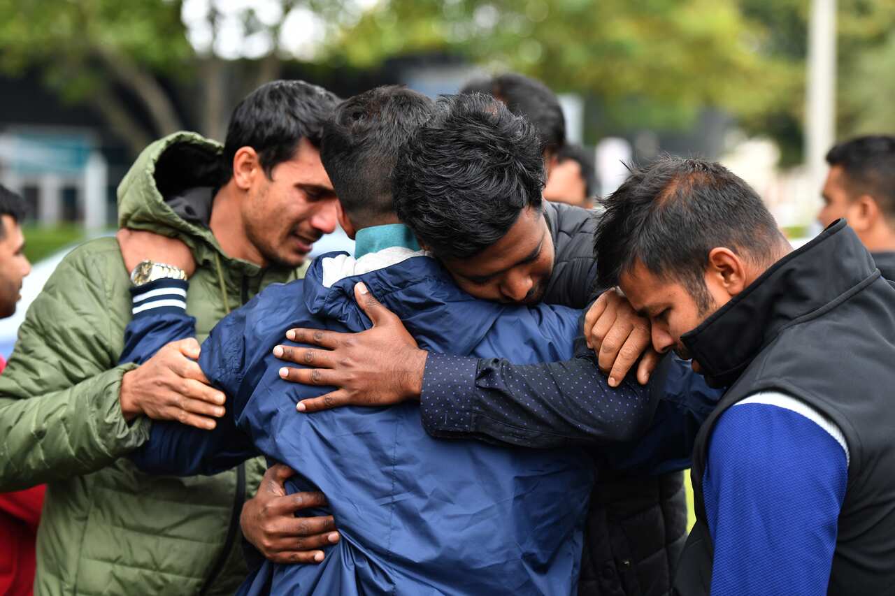 Friends of a missing man grieve outside a refuge centre in Christchurch, Sunday, March 17, 2019.