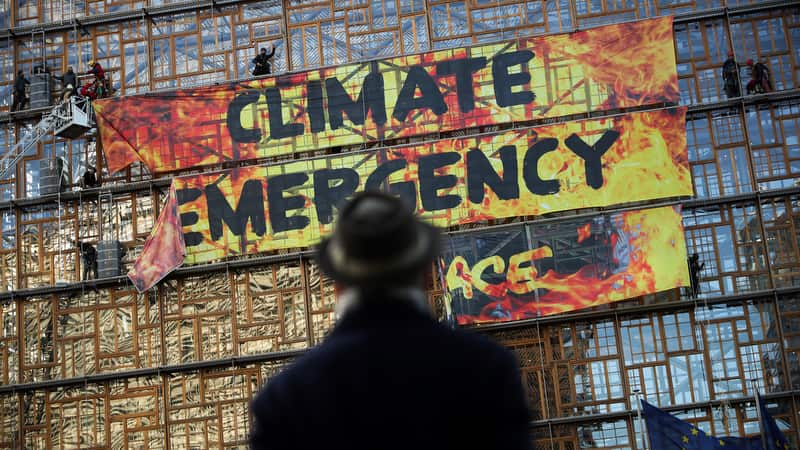 A man looks up as police and fire personnel move in to remove climate activists after they climbed the Europa building. 