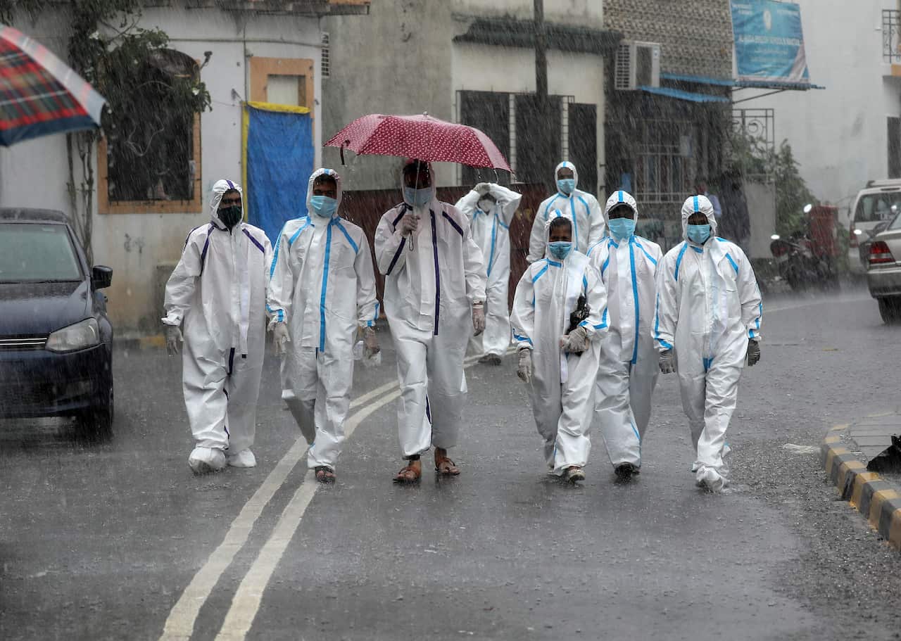 Indian health workers wearing personal protective equipment (PPE) arrive to carry medical checkup of the residents of a 'containment zones' during heavy rains in Mumbai, India, 05 July 2020.