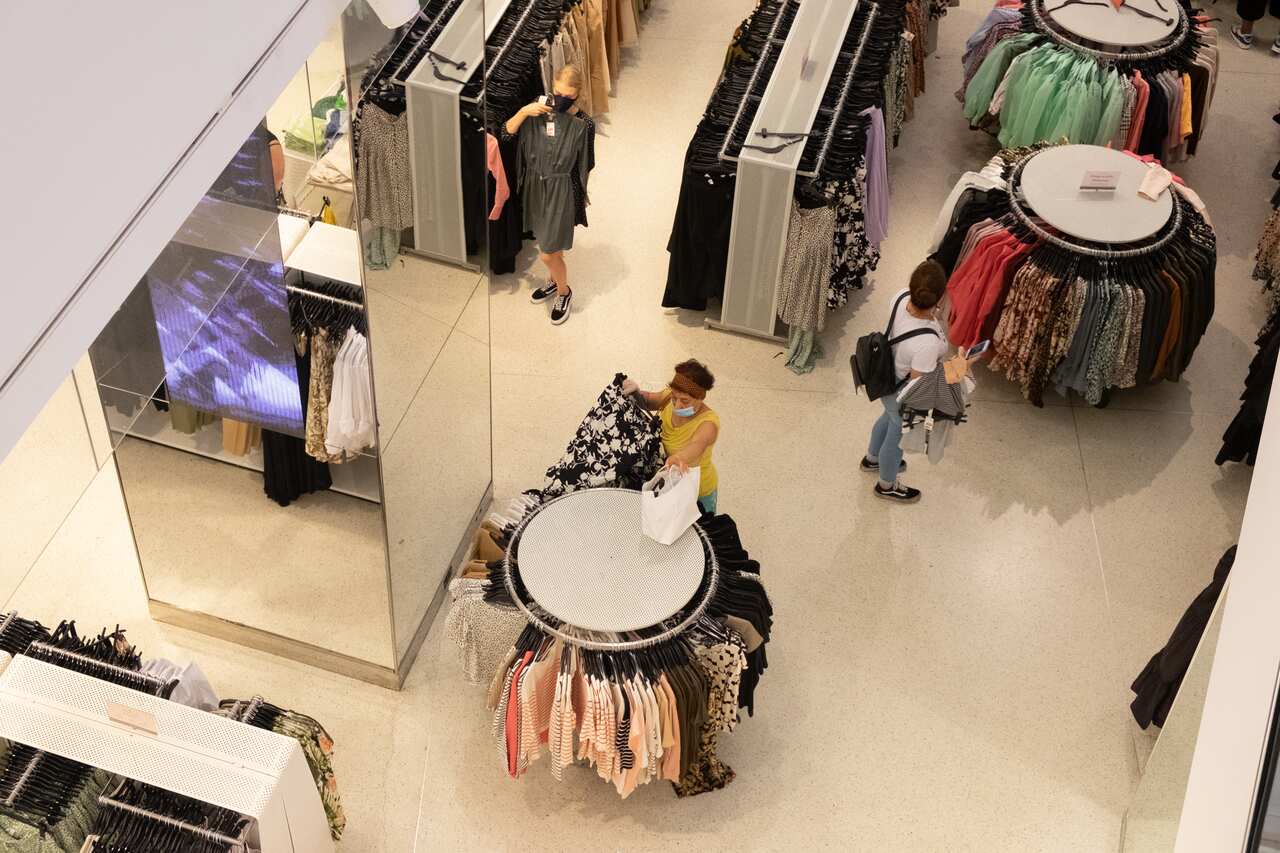 Women wearing face masks look through clothes at a retail store inside Manhattan as the city enters phase 3 of reopening amid the coronavirus pandemic.