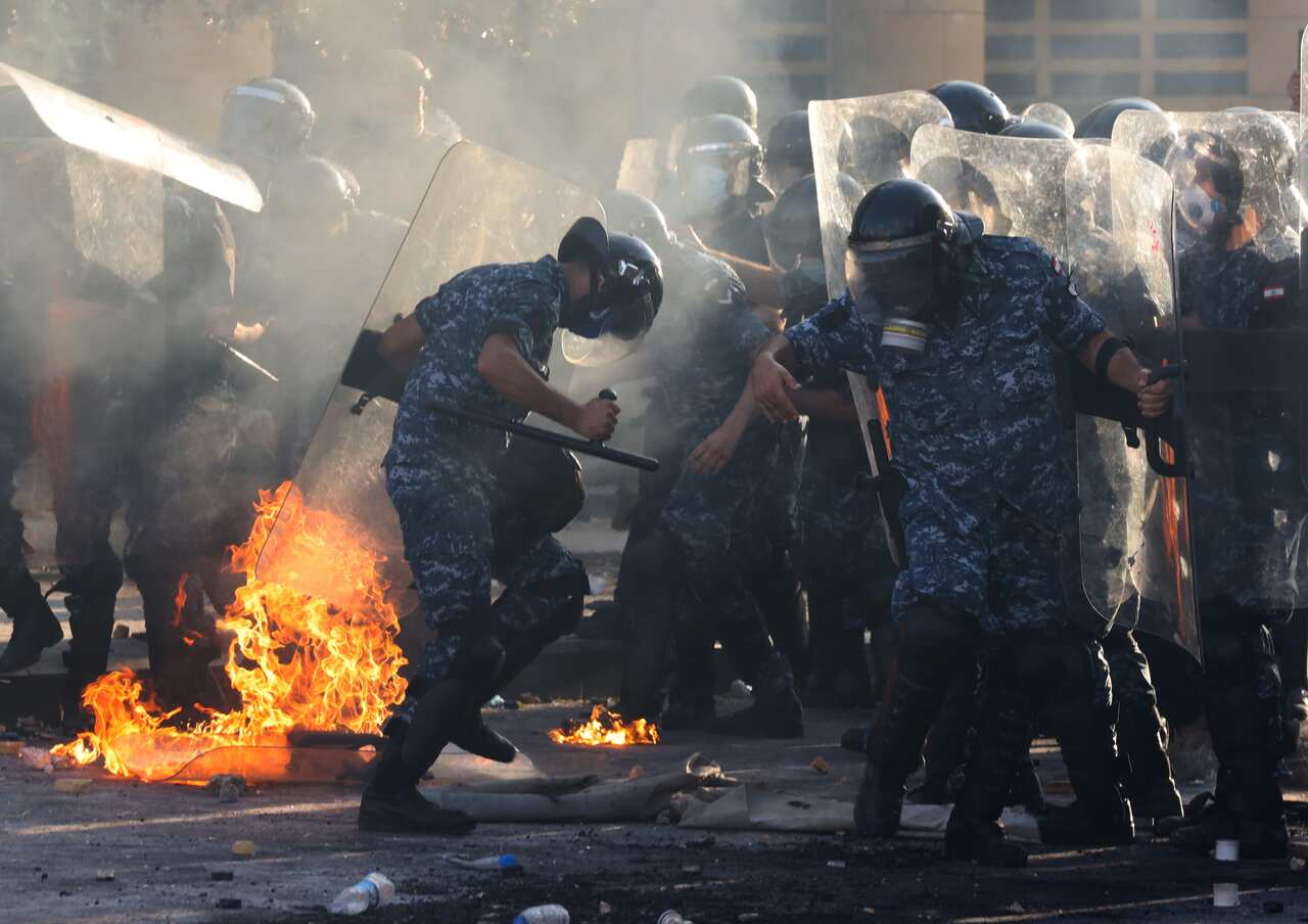 Lebanese riot police try to put out a fire nearby during clashes with anti government protesters at a protest in Beirut, Lebanon, 08 August 2020. 