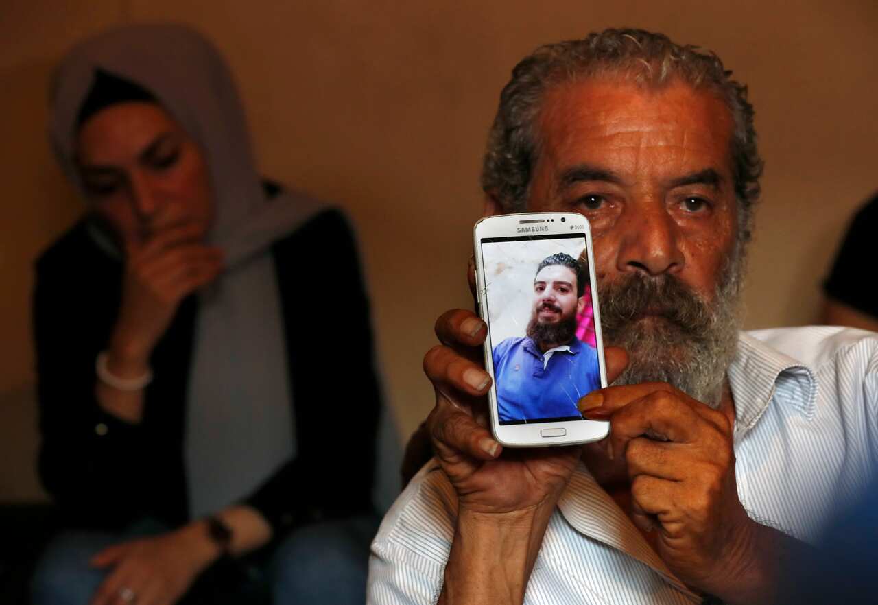 Lebanese Khaldoun Mohammed, 58, shows a portrait of his son Mohammed, 27, who is still missing at sea while he was trying with other migrants to reach Cyprus on a boat, as he sits at his house in Tripoli, north Lebanon Thursday, Sept. 17, 2020. Mohammed i