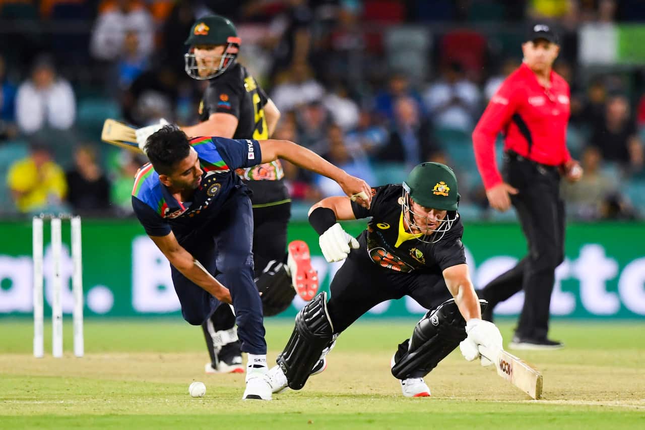 Deepak Chahar of India attempts to run out DArcy Short of Australia during the first T20 cricket match between Australia and India at Manuka Oval.
