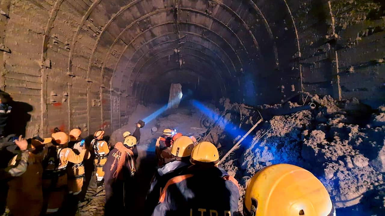 Indo Tibetan Border Police (ITBP) personnel use torches to gain access inside a tunnel to rescue more than three dozen power plant workers trapped inside it 