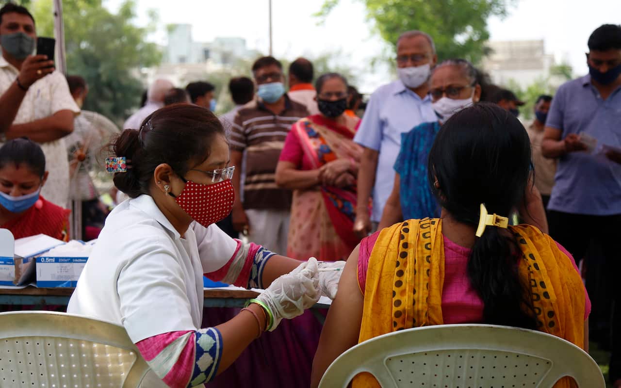A health worker administers the COVISHIELD vaccine for COVID-19 at a residential area in Ahmedabad, India, Sunday, April 4, 2021. (AP Photo/Ajit Solanki)