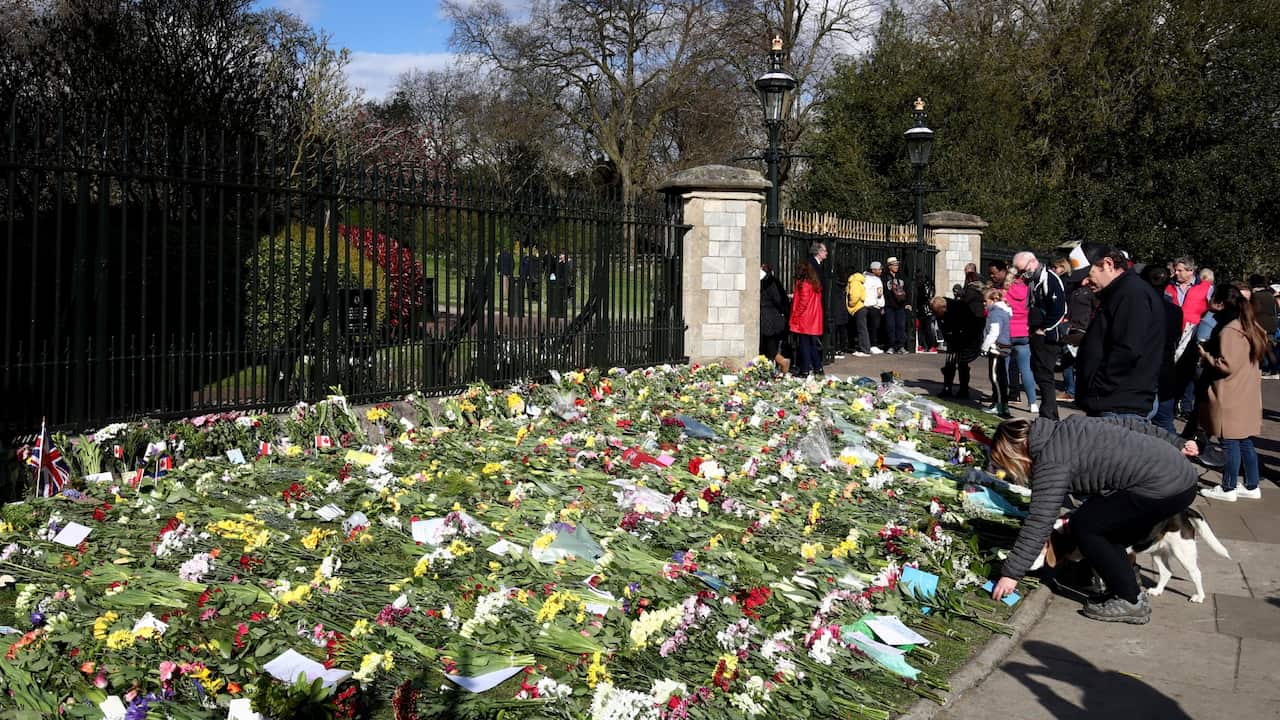 People look at flowers placed outside Windsor Castle, Berkshire, following the announcement of the death of the Duke of Edinburgh at the age of 99 on Friday April 9. Picture date: Sunday April 11, 2021..