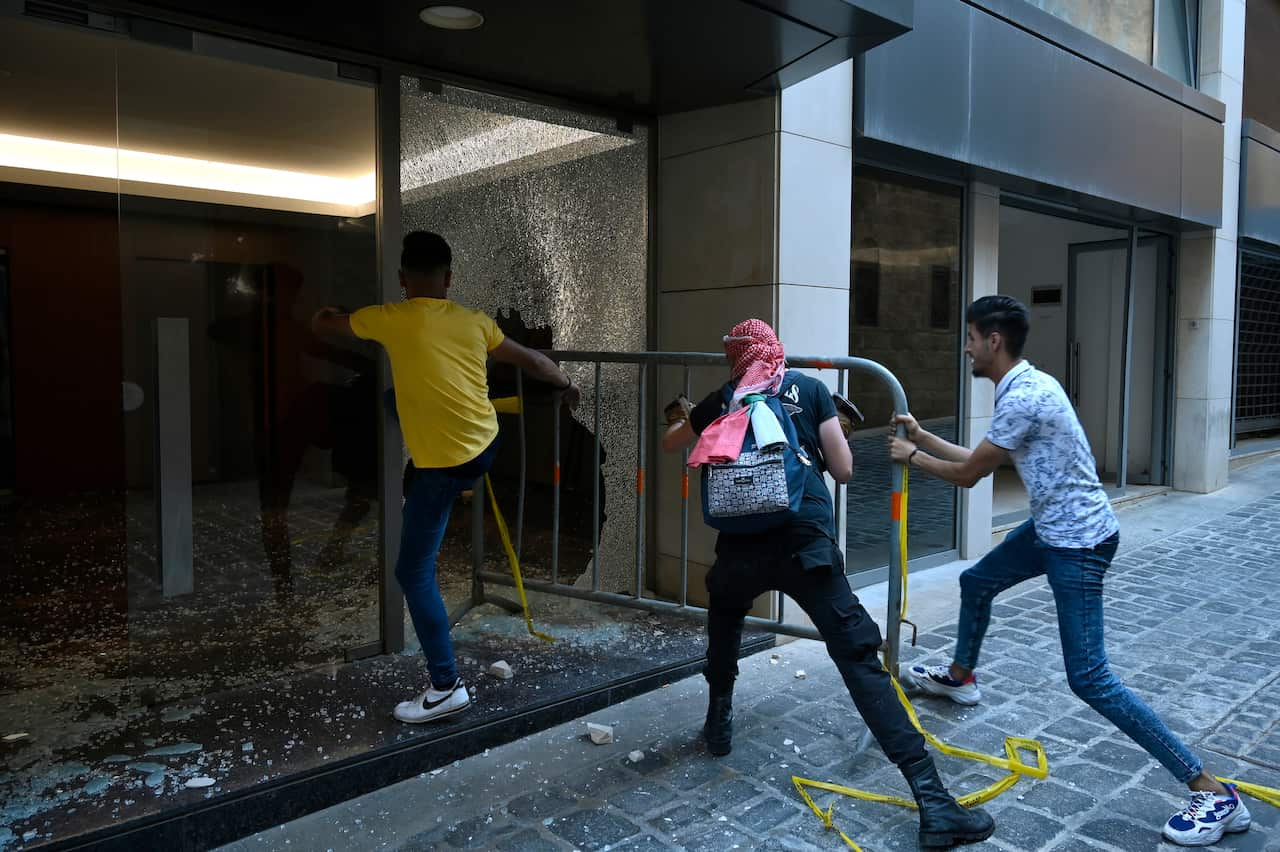 nti-government protesters using a metal barrier to smash glass panels