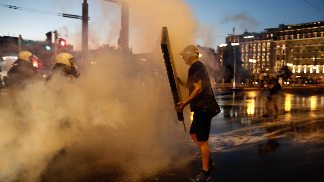 A protester holds a Christian religious icon as he stands in front of a police vehicle during clashes after an anti-vaxxer rally in Athens, Greece, 29 August 2021. Clashes have taken place after an anti-vaxxer rally in Athens' Syntagma Square on Sunday 2