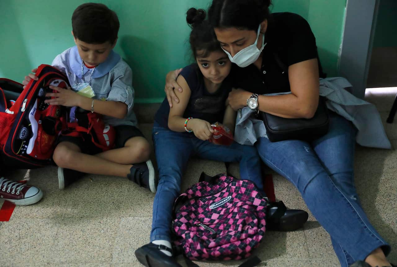 A teacher hugs a student who is afraid of the sounds from nearby armed clashes, at a school, after deadly clashes erupted along a former 1975-90 civil war front-line between Muslim Shiite and Christian areas, at Ain el-Remaneh neighborhood, in Beirut, Leb