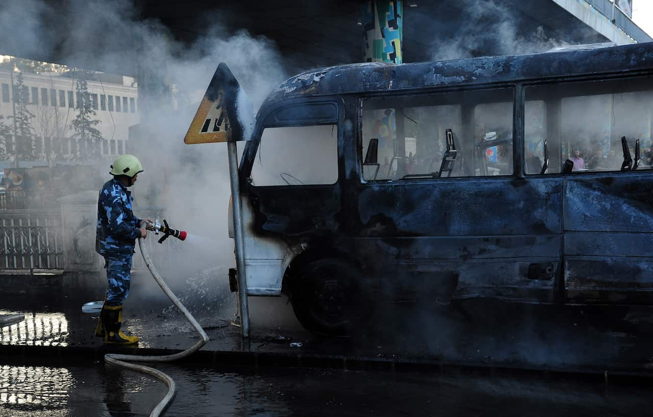 epa09533626 A handout photo made available by SANA (Syrian Arab New Agency) shows firefighters trying to extinguish a damaged bus after explosions in Damascus, Syria, 20 October 2021. Two roadside bombs exploded near a bus carrying troops in early morning