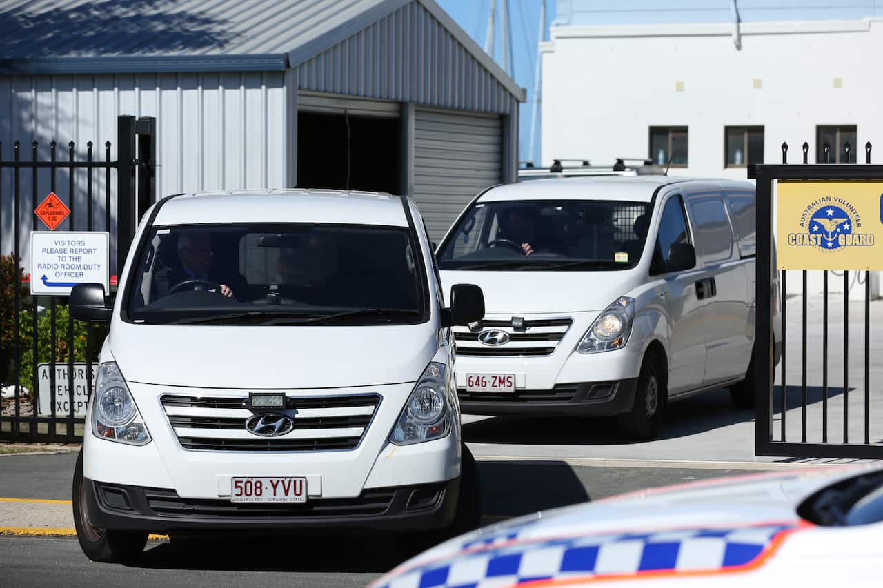 Vans belonging to a funeral home are seen departing the Redcliffe Coast Guard at the Scarborough Marina after a plane crashed into nearby waters, north of Brisbane, Sunday, December 19, 2021. Queensland Police have confirmed two adults and two children h