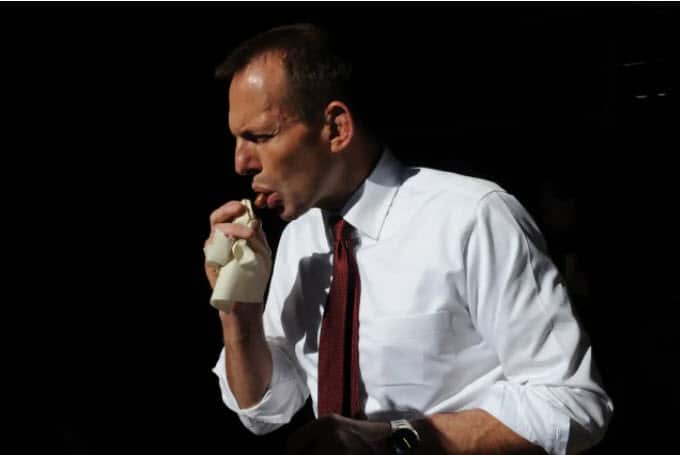 Former prime minister Tony Abbott eats a sausage as he tours Kalgoorlie, Western Australia, during the 2010 election campaign.