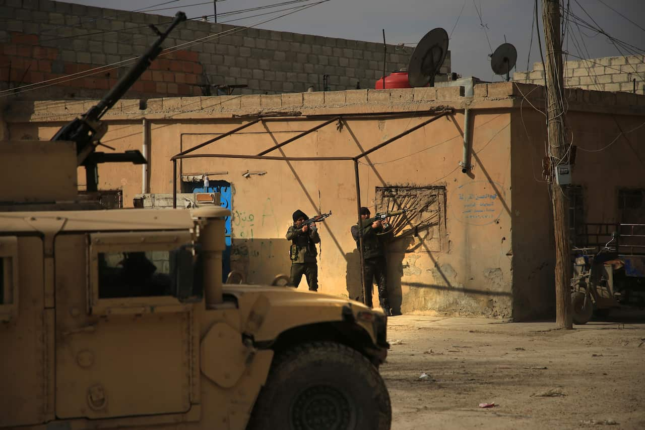 Kurdish-led Syrian Democratic Forces fighters, take their positions at an alley near Gweiran Prison, in Hassakeh, northeast Syria, Sunday, Jan. 23, 2022. Clashes between U.S.-backed Syrian Kurdish fighters and militants continued for a fourth day Sunday n