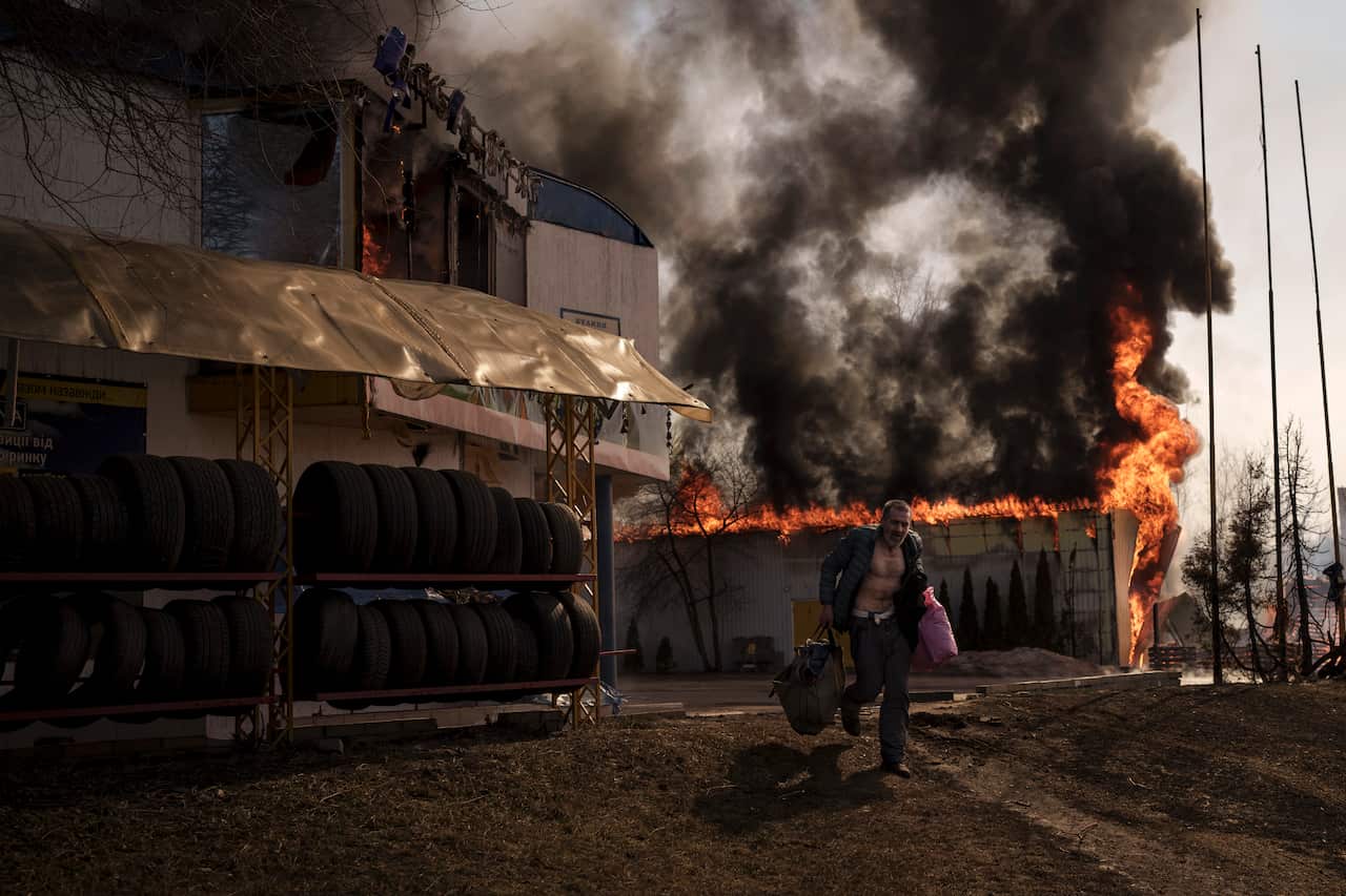 A man recovers items from a burning shop following a Russian attack in Kharkiv, Ukraine, Friday, March 25, 2022. (AP Photo/Felipe Dana)