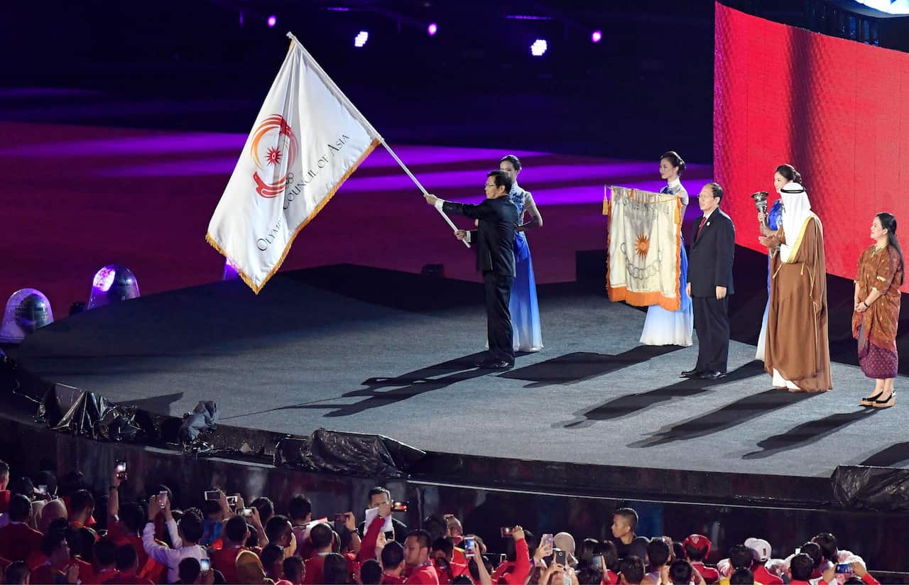 File photo taken Sept. 2, 2018, shows an official from Hangzhou, China, holding the Asian Games flag during the closing ceremony of the games in Jakarta. (Kyodo via AP Images) ==Kyodo