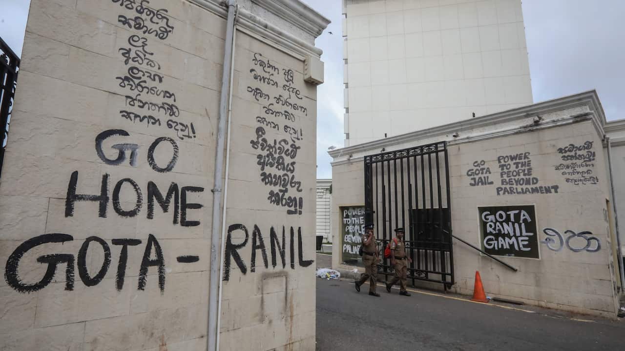 Police officers walk past slogans written on the walls near the President's palace in Colombo, Sri Lanka, 10 July 2022, a day after official residences were stormed.