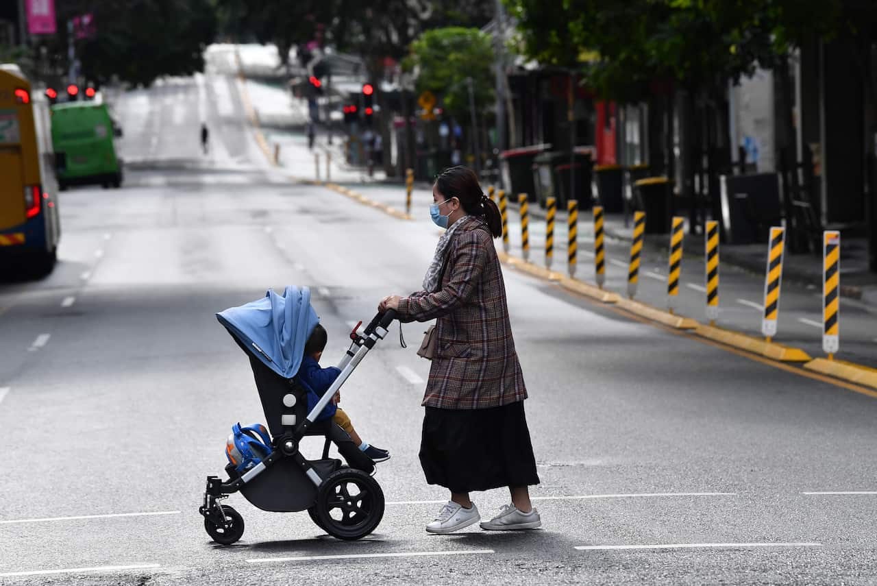 A women pushing a pram is seen crossing an empty Elizabeth Street during lockdown in Brisbane, Wednesday, June 30, 2021.