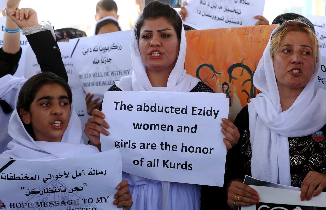raqi Yazidi women hold placards during a protest outside the United Nations (UN) office in the Iraqi city of Arbil, the capital of the autonomous Kurdish region, on August 2, 2015 in support of women from their community who were kidnapped last year in th
