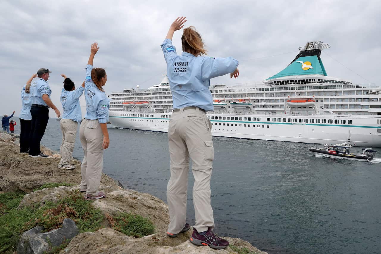 Australian Medical Assistance Team staff who worked with the passengers and crew on the cruise ship Artania wave goodbye as it departs Fremantle harbour.