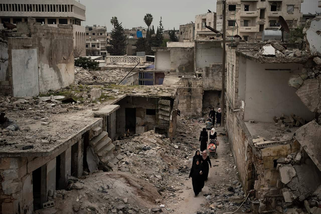 Women walk in a neighbourhood heavily damaged by airstrikes in Idlib, Syria on 12 March 2020.