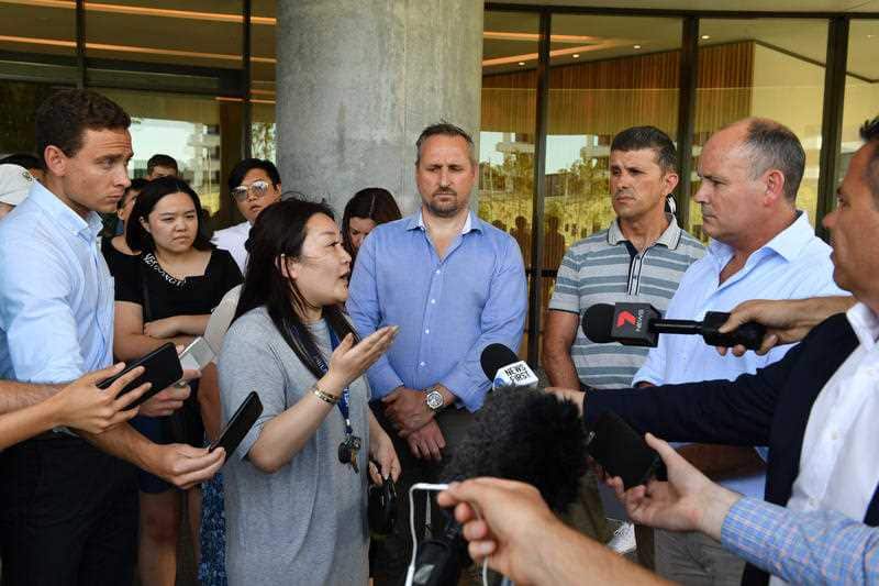 A resident (left) asks questions of Icon Managing Director Julian Doyle at a press conference outside the Opal Tower.